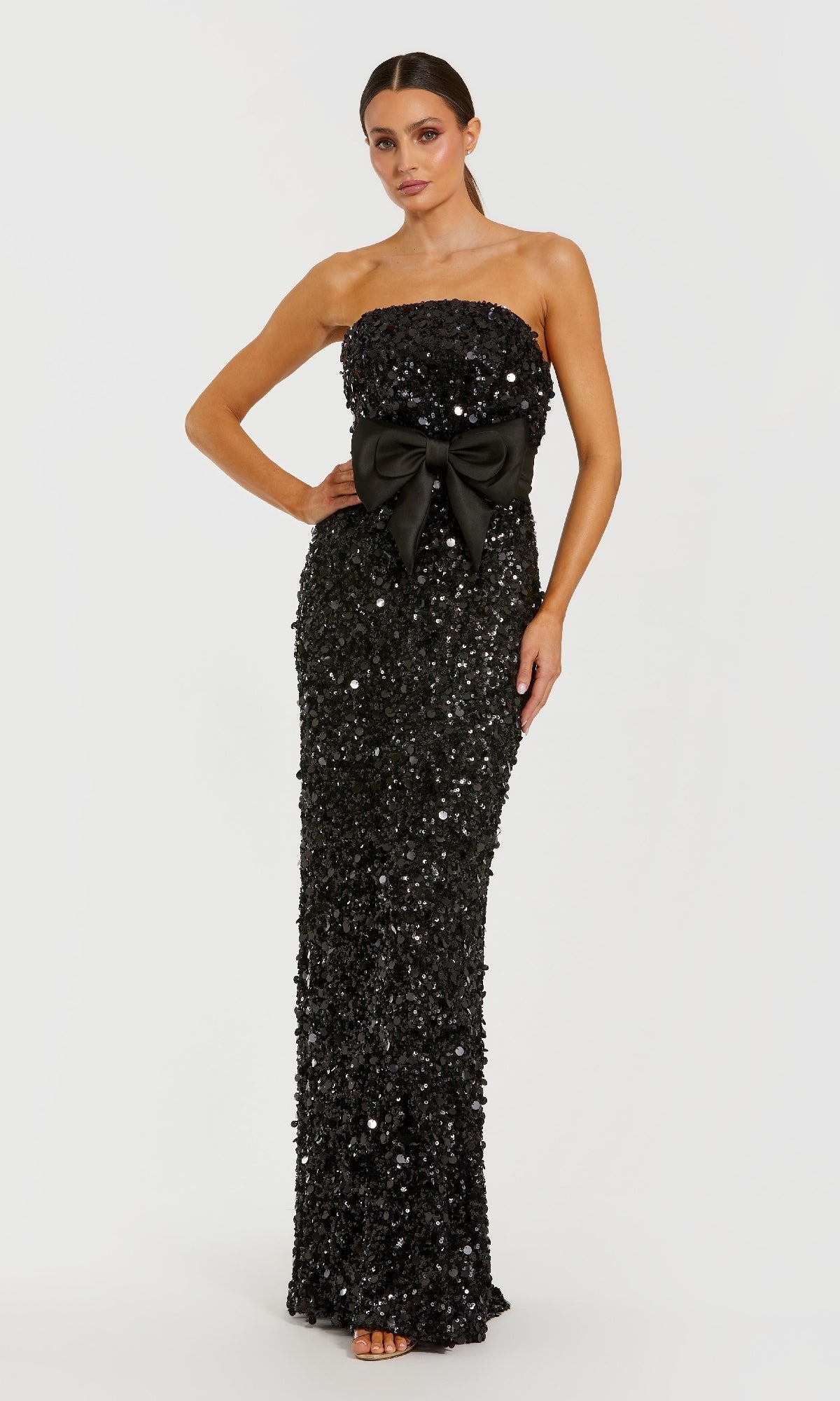 Black sequin strapless gown with a large bow on a white background